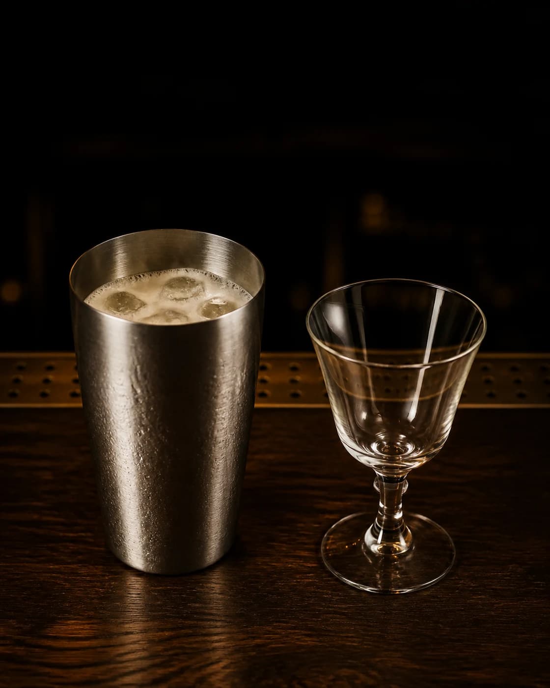 Fine-strain into the goblet stage with cocktail shaker pouring through a fine strainer